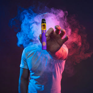 Person holding a vape device with colorful smoke against a dark background
